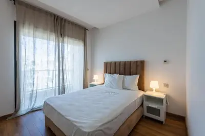 a bedroom with a large bed and a large window at Très bel appartement bien situé Hayriad in Rabat