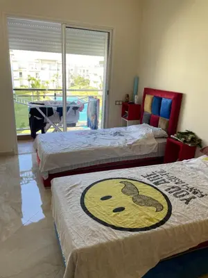 a bedroom with two beds with a picture of a face at Appartement à Casabay SidiRahal in Sidi Rahal