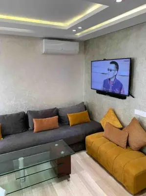 a living room with a couch and a flat screen tv at La location de la mer in Dar Bouazza
