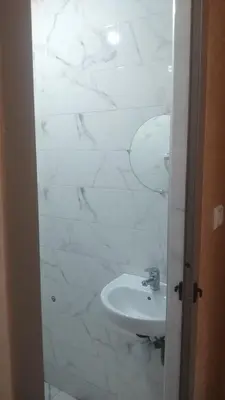 a bathroom with a sink and white marble walls at Sweet Room Airport 5 in Deroua