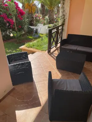 a patio with black chairs and tables and flowers at BOUZNIKA BAY COUNTRY CLUB in Bouznika