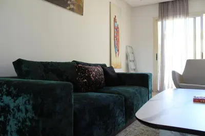 a living room with a green couch and a table at Appt 22 Bloc G- Hicherraton plage Residence Bella Vista, BOUZNIKA BAY in Skhirat