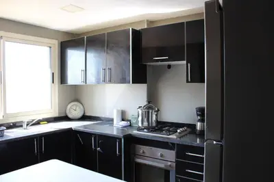 a kitchen with black cabinets and a stove top oven at Appt 22 Bloc G- Hicherraton plage Residence Bella Vista, BOUZNIKA BAY in Skhirat