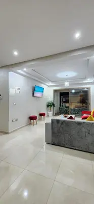 a lobby with a couch and a tv on a wall at COSTA BEACH Lux Family Apartment with Pools in Bouznika