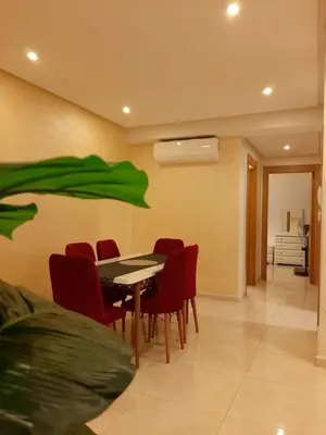 a dining room with a table and red chairs at COSTA BEACH Lux Family Apartment with Pools in Bouznika