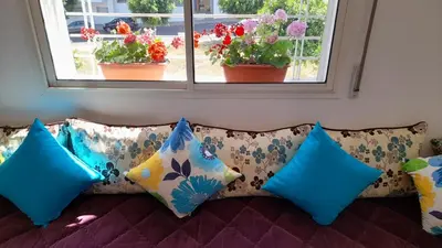 a couch with colorful pillows in front of a window at Tamesna HOUSE in Sidi Yahia az Zaʼer