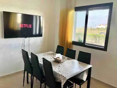 a dining room with a table and chairs and a window at Appartement pieds dans l’eau Tamaris in Casablanca