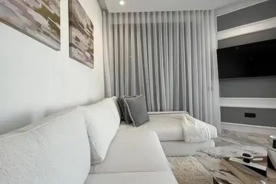 a white living room with a white couch and a tv at Casablanca Downtown 21 - By AppartAli in Casablanca
