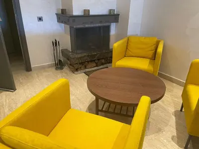 a living room with yellow chairs and a table and a fireplace at APPARTEMENT HAUT STANDING proche gare casa voyageur in Casablanca
