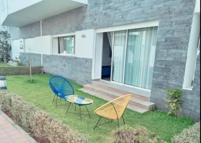 two chairs and a table in front of a house at Appartement luxueux et moderne à sidi Rehal in Dar Hamida