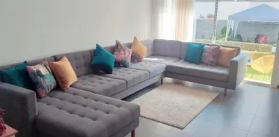 a living room with a gray couch with colorful pillows at Appartement luxueux et moderne à sidi Rehal in Dar Hamida
