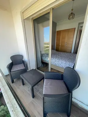 a room with a bed and two chairs on a balcony at Superbe Appt avec grande piscine 2 in Dar Bouazza