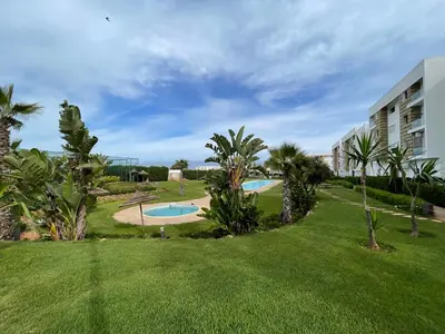 a view of a yard with two pools and palm trees at Superbe Appt avec grande piscine 2 in Dar Bouazza