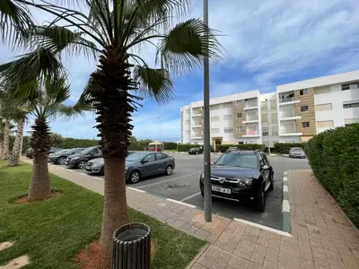 a car parked in a parking lot next to a building at Superbe Appt avec grande piscine 2 in Dar Bouazza