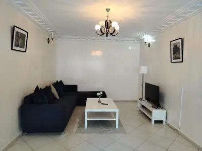 a living room with a black couch and a white table at Appartement Casa Voyageurs in Casablanca