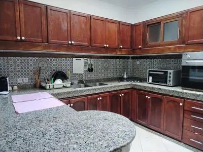 a kitchen with wooden cabinets and a granite counter top at Appartement Casa Voyageurs in Casablanca