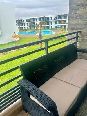 a bench on a balcony with a view of a park at Appartement Cozy avec piscine in Sidi Rahal