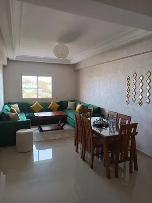 a living room with a green couch and a table at Appartement avec piscine à Mohammedia Plage à 5min in Mohammedia