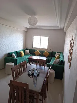 a living room with a green couch and a table at Appartement avec piscine à Mohammedia Plage à 5min in Mohammedia