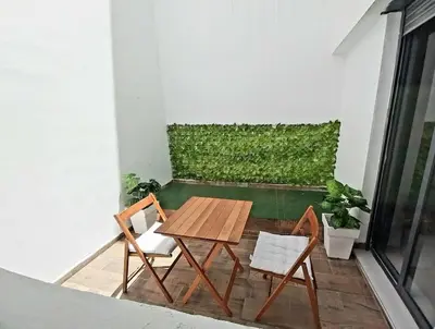 a wooden table and two chairs on a balcony at Appartement cosy proche Aéroport in Deroua
