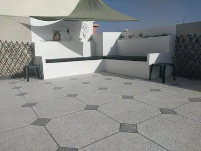 a tiled floor with two benches and an umbrella at Appartement cosy proche Aéroport in Deroua