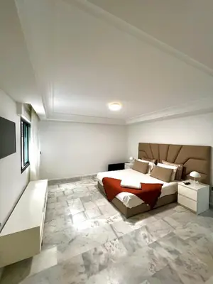 a bedroom with a king sized bed and a couch at Magnifique duplex moderne à 1 minute à pied de la plage- Résidence Miramar Mohammedia in Mohammedia