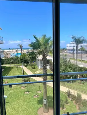 a view of a palm tree from a window at Cosy Apartment with sea view in Sidi Rahal