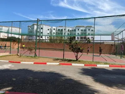 a tennis court with people playing tennis on the court at Appartement mohamedia Ricoflores vue sur piscine in Mohammedia