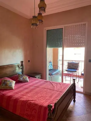 a bedroom with a bed with a red blanket and a balcony at Appartement mohamedia Ricoflores vue sur piscine in Mohammedia