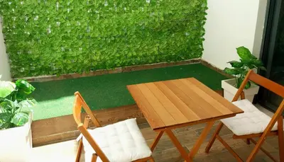 a table and chairs in front of a green wall at Cosy appartement proche de l'aéroport mohamed 5 in Deroua