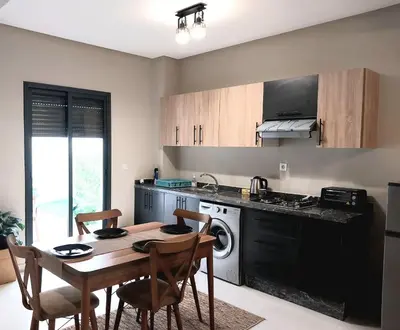 a kitchen with a table and a kitchen with a stove at Cosy appartement proche de l'aéroport mohamed 5 in Deroua