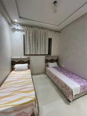 two beds in a small room with purple sheets at Bahia beach . Plage dahomey in Bouznika