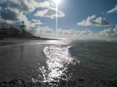 a beach with the sun shining on the water at lovely 2 bedroom vacation home with pool/beach in Skhirat