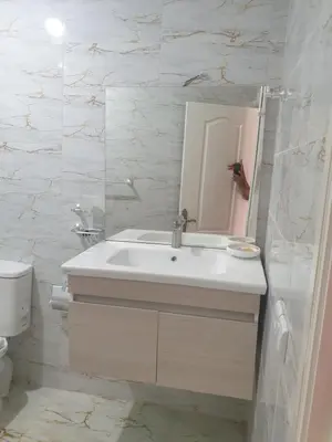 a white bathroom with a sink and a mirror at Appartement Meublé AIN SEBAA in Aïn Sebaa