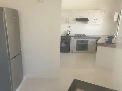a kitchen with a refrigerator and a stove at Appartement Meublé AIN SEBAA in Aïn Sebaa