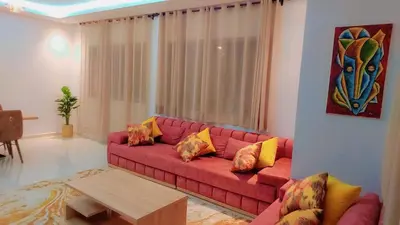 a living room with a red couch and a table at Appartement Nova - Costa Bouznika in Bouznika