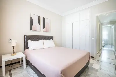 a white bedroom with a large bed and a table at Grand Appartement Vue mer à Ain Diab - Calme Absolu in Casablanca