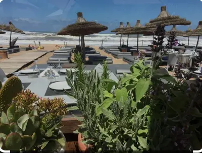 a beach with tables and chairs and umbrellas at Hébergement bord de mer in Casablanca