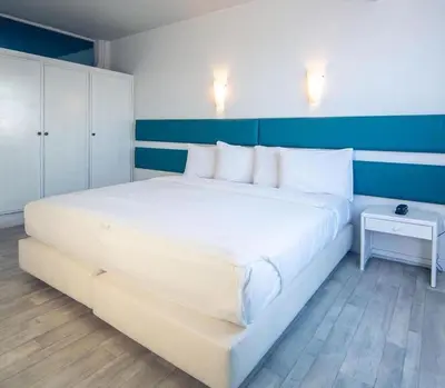 a large white bed in a bedroom with a blue wall at Hotel Tropicana in Casablanca