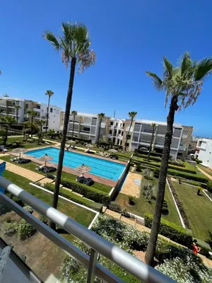 a view of a swimming pool with palm trees at Eden tamaris résidence in Dar Bouazza
