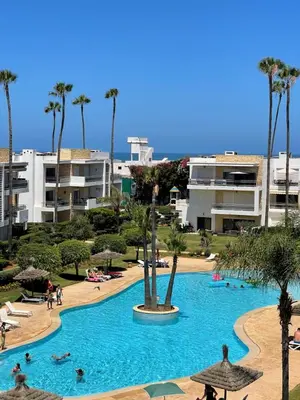 a large swimming pool with people in a resort at Eden tamaris résidence in Dar Bouazza