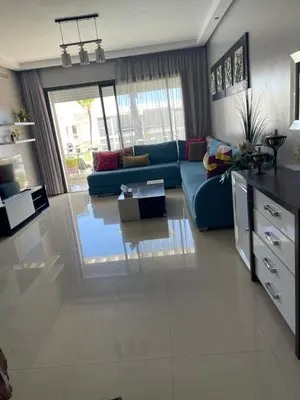 a living room with a blue couch and a table at Eden tamaris résidence in Dar Bouazza