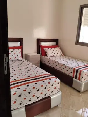 two beds in a small room with at Appartement Cozy Louizia in Ben Yakhlef