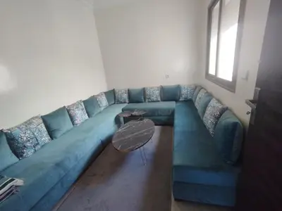 a blue couch in a living room with a table at Appartement Cozy Louizia in Ben Yakhlef