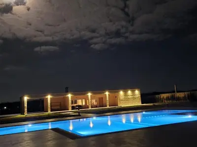 a building with a swimming pool at night at Ferme d'hôte Evasio in Sidi Rahal