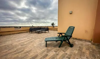 a patio with a green chair and tables on a roof at Ferme d'hôte Evasio in Sidi Rahal