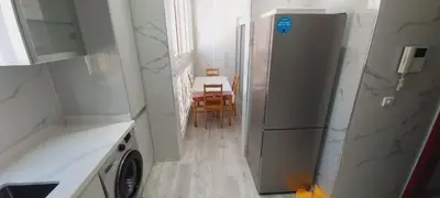 a kitchen with a refrigerator and a table at Residence Al Kawtar in Mohammedia