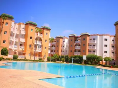 a swimming pool in front of some apartment buildings at Residence Al Kawtar in Mohammedia