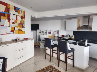 a kitchen with white cabinets and bar stools at Appartement Luxueux vue Mer dans Résidence avec piscines et jardin in Dar Bouazza