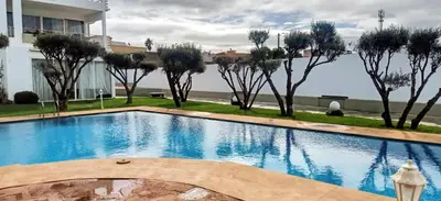 a large swimming pool with trees in the background at Appartement Luxueux vue Mer dans Résidence avec piscines et jardin in Dar Bouazza